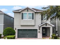 Two-story house with gray siding, dark green garage door, and landscaping at 7617 Brookhurst Ln, Kissimmee, FL 34747