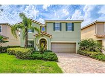 Two-story house with a green facade, brick driveway and landscaping at 11874 Aurelio Ln, Orlando, FL 32827