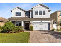 Two-story house with gray siding, stone accents, and a three-car garage at 3425 Halsway Dr, Orlando, FL 32824