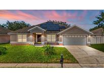 Two-story house with solar panels, a gray garage door, and landscaped yard at 2090 Big Buck Dr, St Cloud, FL 34772