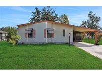 Single-wide mobile home with carport and well-maintained lawn at 450 Tivoli Park Dr, Davenport, FL 33897