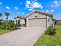 Tan house with a two-car garage and landscaping at 4743 Magnetite Loop, Mount Dora, FL 32757