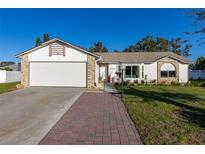 White house with brick accents, a two-car garage, and a landscaped yard at 1402 Westminster Way, Kissimmee, FL 34744