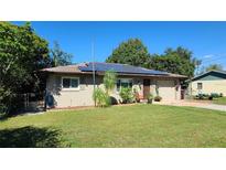 Tan brick home with solar panels and a well-manicured lawn at 112 10Th St, St Cloud, FL 34769