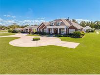 Brick home with circular driveway, landscaping, and detached guest house at 2780 Vickie Ct, Kissimmee, FL 34744