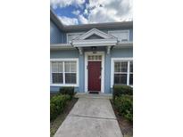 Inviting exterior of a light blue building with a red door and well-manicured landscaping at 2280 San Vital Dr # 105, Kissimmee, FL 34741