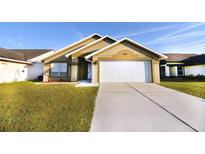 Tan house with white garage door and green lawn at 8815 Parliament Ct, Kissimmee, FL 34747