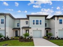 Two-story light teal townhome with attached garage and landscaping at 742 Longboat Dr, Davenport, FL 33896