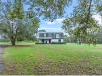 White ranch home with gray roof and red front door, nestled in a spacious yard at 965 Keen Rd, Frostproof, FL 33843