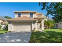 Two-story house with a beige exterior, a two-car garage and lawn at 2421 Huron Cir, Kissimmee, FL 34746