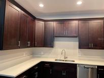 Modern kitchen with dark brown cabinets, quartz countertops, and stainless steel appliances at 221 Elm Ct, Poinciana, FL 34759