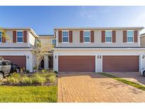Two-story townhome with a two-car garage and landscaped yard at 4919 Conifer Cone Dr, Kissimmee, FL 34746