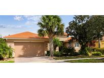 Tan house with terracotta roof, two-car garage, and lush landscaping at 561 Sienna Dr, Poinciana, FL 34759
