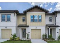 Two-story townhome with light-colored siding and a two-car garage at 709 Benoi Dr, Davenport, FL 33896