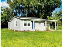 Newly renovated home with gray siding, landscaping, and a blue door at 639 Shore Acres Dr, Lakeland, FL 33801
