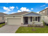 One-story house with light beige siding, a two-car garage, and a landscaped yard at 2971 Camden Way, Davenport, FL 33837