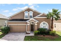 Two-story house with a brown exterior, two-car garage and palm tree at 131 Cadiz Loop, Davenport, FL 33837