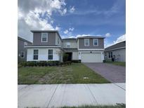 Two-story home with a gray and purple exterior, two-car garage, and manicured lawn at 2737 Nottel Dr, Saint Cloud, FL 34772