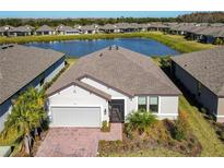 Single-story home with a gray roof and brick driveway, situated on a lake at 445 Via Abruzzi St, Poinciana, FL 34759