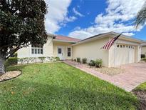 Single-story home with landscaped lawn, brick paver driveway, and attached garage at 141 Marabella Loop, Poinciana, FL 34759