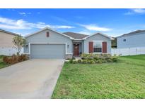 Gray house with red shutters, two-car garage, and landscaped lawn at 356 Citrine Loop, Kissimmee, FL 34758
