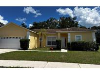 Single-story house with attached garage, landscaping, and a yellow exterior at 481 Peppermill Cir, Kissimmee, FL 34758