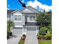 Two-story townhome with gray siding, two-car garage, and landscaping at 1060 Rock Harbor Ave, Orlando, FL 32828