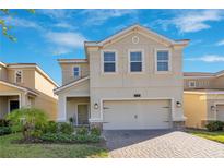 Two-story house with tan siding, two-car garage, and landscaped front yard at 1081 Trappers Trail Loop, Davenport, FL 33896