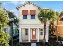 Bright yellow house with orange accents, palm trees, and a brick walkway at 3075 Key Lime Loop, Kissimmee, FL 34747