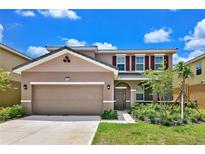 Two-story home with a large garage and landscaped yard at 7635 Oakmoss Loop, Davenport, FL 33837