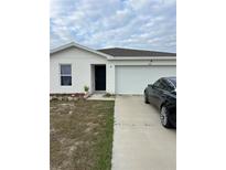 White house with a two-car garage and a black car parked in the driveway at 106 Orchid Ct, Kissimmee, FL 34759