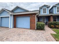 Two-story light blue house with brick garage and paver driveway at 3480 Home Town Ln, Saint Cloud, FL 34769