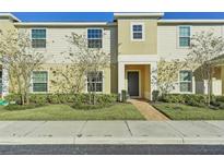 Two-story townhome with light beige siding, landscaping, and a paved walkway at 439 Annabelle Way, Davenport, FL 33837
