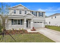 Two-story house with gray siding, stone accents, and a two-car garage at 670 Summit River Dr, Apopka, FL 32712