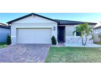 One-story home with a two-car garage, landscaped yard, and brick paver driveway at 161 Andreas St, Winter Haven, FL 33881