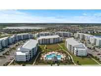 Aerial view of apartment community featuring a pool, lake, and multiple buildings at 3151 Paradox Cir # 201, Kissimmee, FL 34746