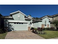 Light teal house with stone accents, two-car garage, and landscaped yard at 4437 Azure Isle Way, Kissimmee, FL 34744