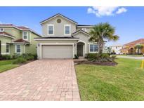 Two-story house with a gray exterior, two-car garage, and a brick paved driveway at 4449 Shiva Loop, Kissimmee, FL 34746