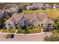 Aerial view of apartment buildings, with ample parking and surrounding landscape at 2302 Butterfly Palm Way # 303, Kissimmee, FL 34747