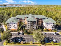 Aerial view of a three-story condo building with parking and lush green surroundings at 9051 Treasure Trove Ln # 207, Kissimmee, FL 34747
