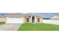 Cute one-story house with a white garage door and a teal front door at 504 Finch Ct, Kissimmee, FL 34759