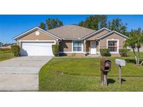 Tan house with a white garage door and green lawn at 60 Andora Ct, Kissimmee, FL 34758