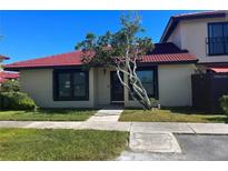 Exterior view of a charming condo with a red tile roof and well-maintained landscaping at 453 Hunter Circle, Kissimmee, FL 34758