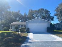 House exterior featuring a light blue vinyl-sided home with a two-car garage and landscaped lawn at 5062 El Destino Dr, Leesburg, FL 34748