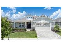 One-story home with gray siding, a two-car garage, and a landscaped lawn at 1790 Flourish Ave, Kissimmee, FL 34744