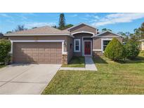 One-story house with brown siding, red door, and attached garage, nestled on a landscaped lawn at 1878 Monte Cristo Ln, Kissimmee, FL 34758