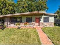 Ranch style home with a coral door, stone accents, and a carport at 309 Poinciana Cir, Kissimmee, FL 34744