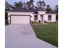 White house with black accents, two-car garage, and a well-manicured lawn at 15265 Sw 29Th Terrace Rd, Ocala, FL 34473