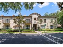 Tan two-story building with balconies, lush landscaping, and a tree-lined street at 701 Westpark Way # 202, Celebration, FL 34747