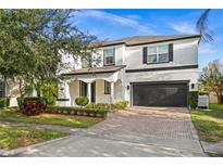 Two-story house with a white exterior, black accents, and a paved driveway at 9111 Outlook Rock Trl, Windermere, FL 34786